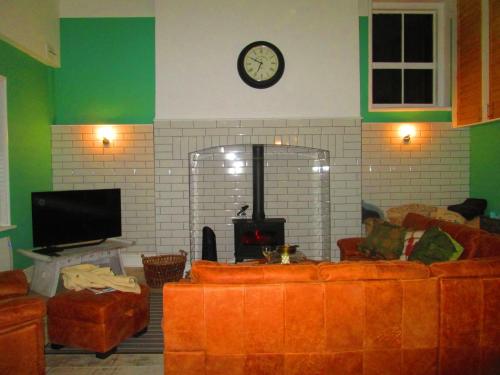 a living room with a couch and a clock on the wall at Weston Manor in Freshwater