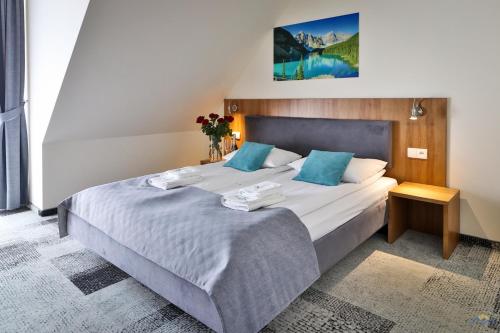 a bedroom with a large bed with blue pillows at Hotel Bystra in Białka Tatrzanska