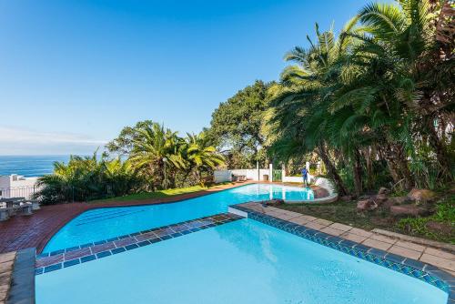a large swimming pool with palm trees and the ocean at Santorini - Perissa 22 in Ballito