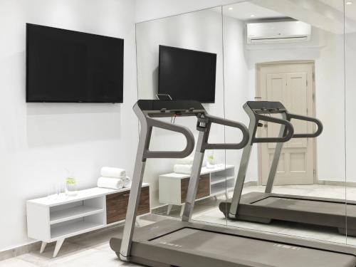 a living room with a treadmill and a flat screen tv at Astra Suites in Imerovigli
