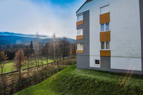 a building on a hill with a view of a field at Apartamenty Izerskie - ul. Cicha 13F-G in Świeradów-Zdrój