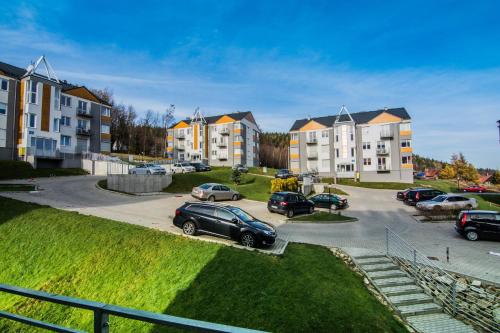a parking lot with cars parked in front of buildings at Apartamenty Izerskie - ul. Cicha 13F-G in Świeradów-Zdrój