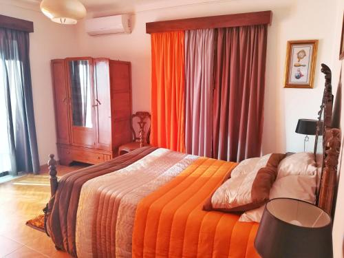 a bedroom with a bed with an orange comforter at Casa Rafael in Belmonte