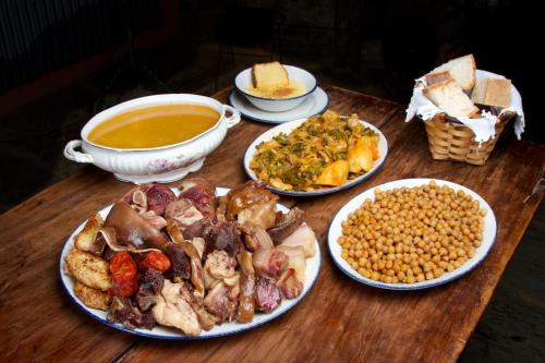a table with plates of food and a bowl of soup at Casa Pepa Hotel Rural in Santa Colomba de Somoza