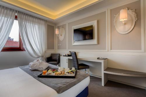 una habitación de hotel con una bandeja de comida en una cama en Grande Albergo Roma en Piacenza