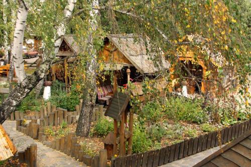 a wooden house with a garden in front of a fence at Комплекс відпочинку "Колиба" in Korostenʼ
