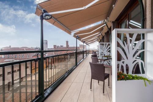 a balcony with chairs and an umbrella on a building at Grande Albergo Roma in Piacenza
