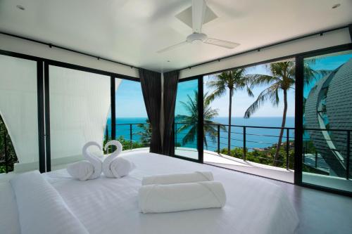 a bedroom with a white bed with a view of the ocean at Villa The Spot Koh Samui in Chaweng Noi Beach