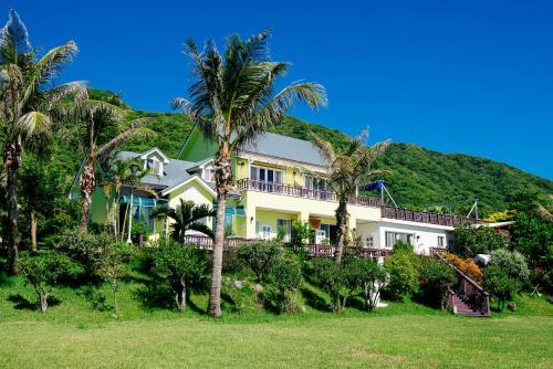 a house with palm trees in front of a hill at 近月旭海莊園民宿 in Yanliau