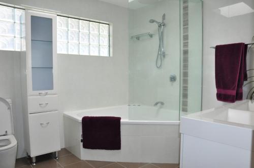 ein weißes Badezimmer mit einer Badewanne und einem Waschbecken in der Unterkunft Double Island Dream in Rainbow Beach