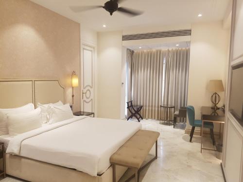 a bedroom with a large white bed and a desk at Hotel Harbour View Colaba in Mumbai
