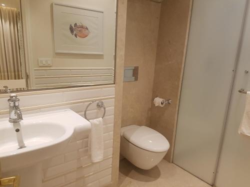 a white bathroom with a sink and a toilet at Hotel Harbour View Colaba in Mumbai