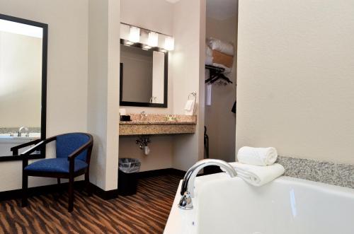 La salle de bains est pourvue d'une baignoire, d'un lavabo et d'une chaise. dans l'établissement Cobblestone Inn & Suites - Manning, à Manning