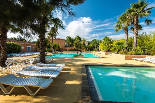 a swimming pool with lounge chairs and palm trees at Camping La Pinède Enchantée in Argelès-sur-Mer