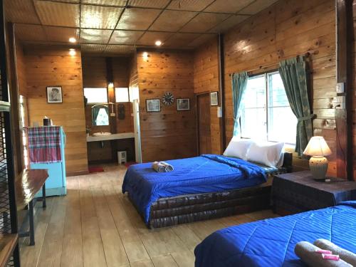 a bedroom with two beds in a room with wooden walls at Dreamhome Chiangdao in Chiang Dao