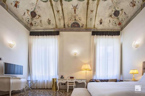 een hotelkamer met 2 bedden en een plafond bij Palazzo Galletti Abbiosi in Ravenna