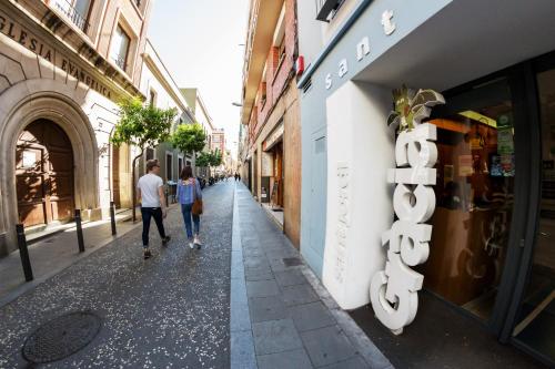 a couple walks down a street in a city at Sant Jordi Hostels Gracia in Barcelona