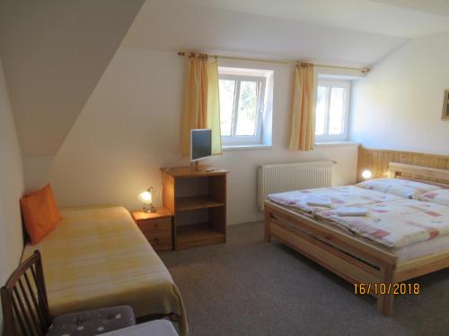 a bedroom with a bed and a desk and a tv at Guest House U Marie in Pec pod Sněžkou