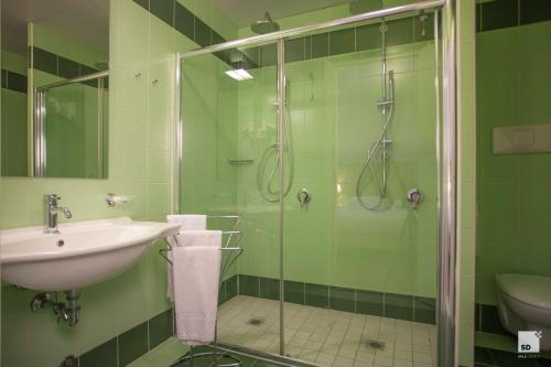 baño verde con lavabo y ducha en Palazzo Galletti Abbiosi, en Rávena