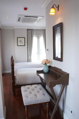 a room with two beds and a table and a mirror at Hiranyakul House in Bangkok