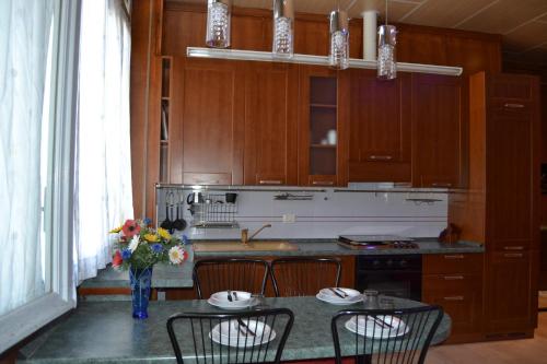 a kitchen with wooden cabinets and a table with chairs at Appartamenti Lago di Como in Valbrona