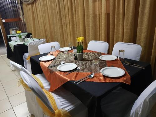 una mesa con platos blancos y flores en ella en Rainbow Guest House and Tours, en Uitenhage