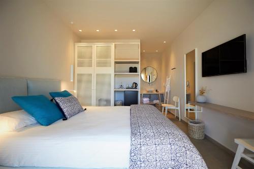 a bedroom with a large white bed with blue pillows at Vigla Hotel in Aegiali