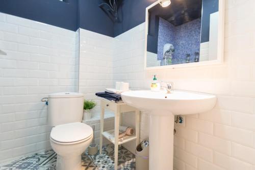 a bathroom with a white toilet and a sink at Edificio 10 by Plaza Mayor Apartamentos in Valladolid