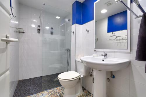 a white bathroom with a toilet and a sink at Edificio 10 by Plaza Mayor Apartamentos in Valladolid