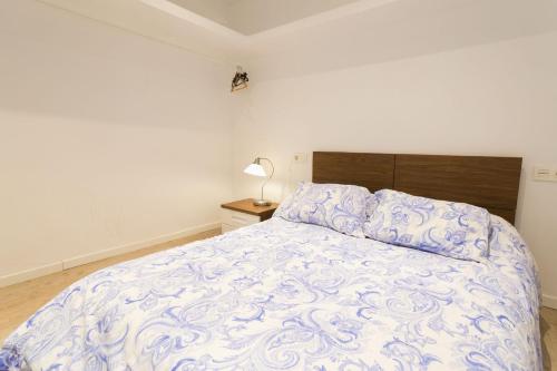 a bedroom with a bed with a blue and white comforter at Edificio 10 by Plaza Mayor Apartamentos in Valladolid