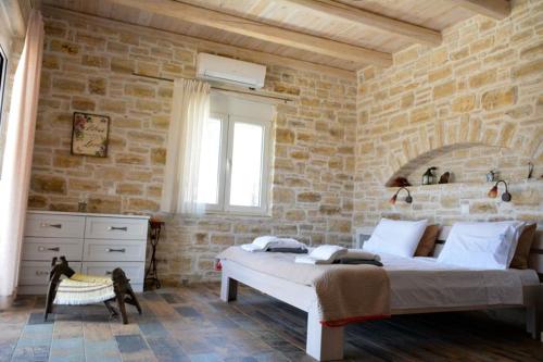 a bedroom with a large bed in a stone wall at Villa Petra in Kamilari