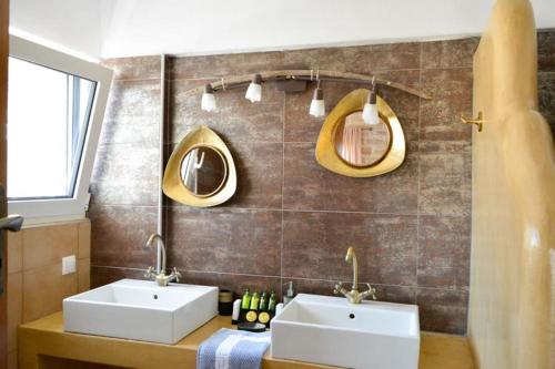 a bathroom with two sinks and two mirrors at Villa Petra in Kamilari
