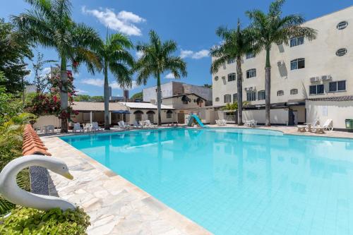 einem großen Pool mit Palmen und einem Gebäude in der Unterkunft Iguassu Flats Hotel in Foz do Iguaçu