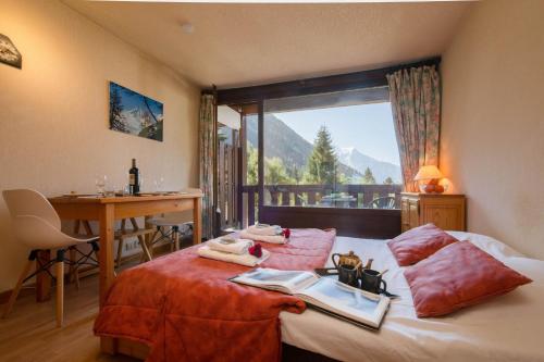 a bedroom with a bed with a table and a window at Résidence La Verte 15 ski in ski out - Happy Rentals in Chamonix