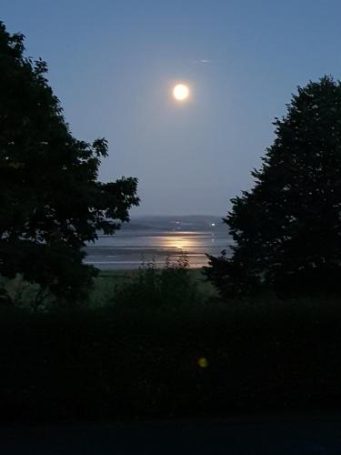 a full moon rising over the ocean at dusk at Grange Boutique Hotel in Grange Over Sands
