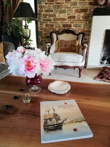 a table with a book and flowers and a chair at Villa Gaia Trikala in Lygariá