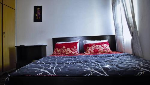 1 dormitorio con 1 cama con almohadas rojas en Dumeros en Abuja