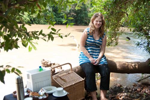a woman sitting on a tree branch next to a river at Mahoora Yala - by Eco Team in Yala