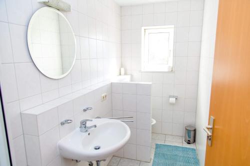 a white bathroom with a sink and a mirror at Taverna Unik in Saaldorf