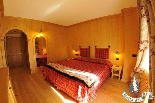a bedroom with a bed with a red blanket at Hotel Baita Dei Pini in Bormio