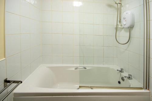a white bath tub with a shower in a bathroom at 7 Varis Apartments in Forres