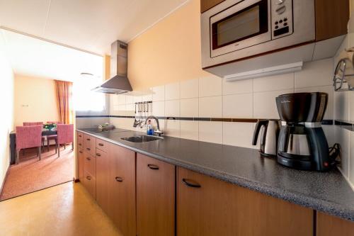 a kitchen with a sink and a microwave at Appartementen de Strandloper in Bergen aan Zee