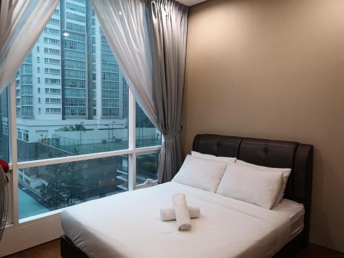 Soho Suites Klcc By Pnut KLCC VIEW في كوالالمبور: سرير عليه منشفتين امام النافذة