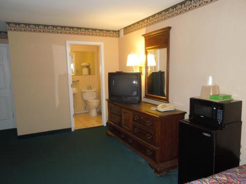 a hotel room with a television on a dresser and a bathroom at Value Inn East Stroudsburg in Marshalls Creek
