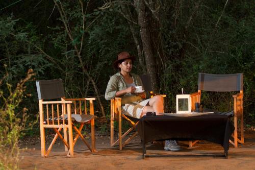a woman sitting in a chair with a cup of coffee at Mahoora Wilpattu - by Eco Team in Wilpattu