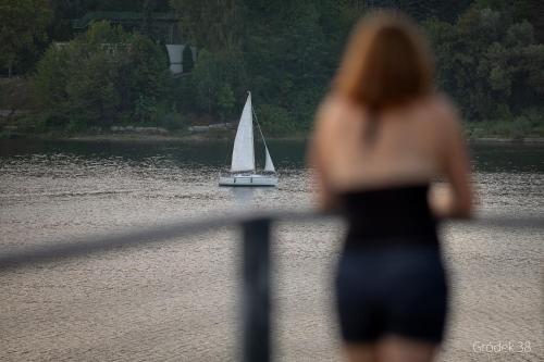 a woman is looking at a sail boat in the water at Apartment Słoneczny Gródek 38 in Gródek Nad Dunajcem