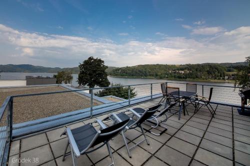 a balcony with chairs and tables and a view of a river at Apartment Słoneczny Gródek 38 in Gródek Nad Dunajcem