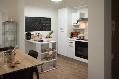 a kitchen with white cabinets and a wooden table at guest house for you in Modena