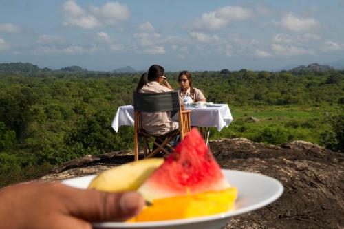two people sitting at a table with a plate of fruit at Mahoora Udawalawe - by Eco Team in Udawalawe