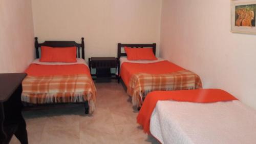 two beds in a room with red and orange sheets at Casa Vieja Posada in Pesca
